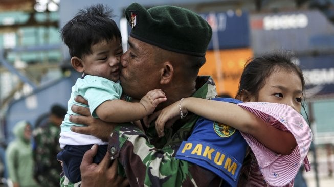 Seorang prajurit TNI AD dari Batalyon Infanteri Raider 142/Ksatria Jaya menggendong kedua anaknya usai mengikuti upacara pemberangkatan Satgas Pamtas RI-RDTL Sektor Timur di Pelabuhan Boom Baru Palembang, Sumatera Selatan, Rabu (28/8). [ANTARA FOTO/Nova Wahyudi]