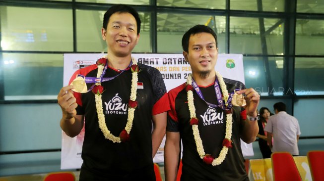 Pebulutangkis ganda putra Indonesia, Hendra Setiawan dan Mohammad Ahsan menunjukan medali emas di Terminal 3, Bandara Soekarno Hatta, Tangerang, Banten, Selasa (27/8).[Suara.com/Arya Manggala]