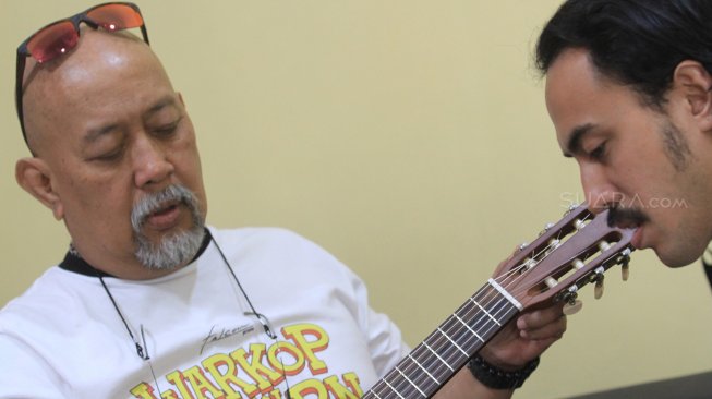 Indro warkop memainkan ukulele saat berkunjung ke kantor Redaksi Suara.com, Jakarta, Jumat (30/8). [Suara.com/Oke Atmaja]