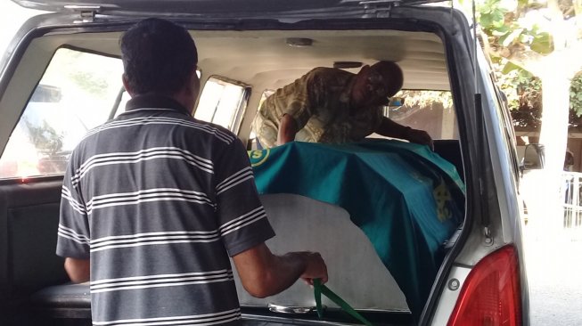 Sopir ambulans Unit Pelayanan Paguyuban Belasungkawa RW 02 Desa Kedunguter, Poniman meletakkan jenazah korban pembunuhan untuk dibawa ke rumah duka, Kamis (29/8/2019). [Suara.com/Teguh Lumbiria]