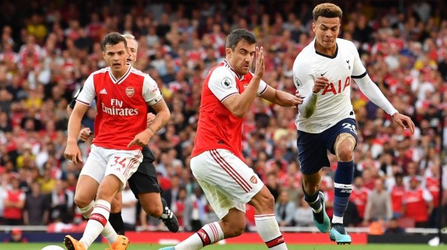 Gelandang serang Tottenham Hotspur, Dele Alli (kanan) berduel dengan bek Arsenal, Sokratis (tengah) pada laga pekan keempat Liga Inggris 2019/2020 di Emirates Stadium, Senin (2/9/2019) dini hari WIB. [Ben STANSALL / AFP]