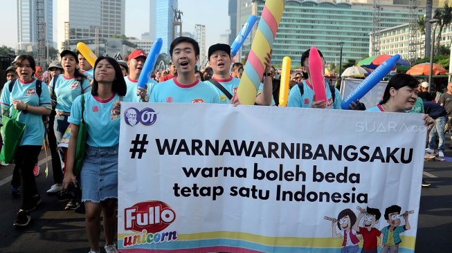 Sejumlah karyawan Orang Tua (OT) Group membentangkan spanduk "Fullo Unicorn" yang telah ditempelkan stiker oleh warga saat parade simpatik Hari Pelanggan Nasional 2019 di kawasan Monas, Jakarta, Minggu (1/9).[Suara.com/Oke Atmaja]