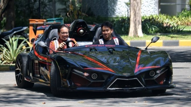 Rektor Institut Teknologi Sepuluh Nopember (ITS) Surabaya Mochamad Ashari (kiri) mengemudikan mobil listrik Lowo Ireng Reborn di ITS Surabaya, Jawa Timur. [Antara/Didik Suhartono]