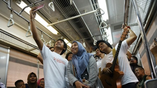 Grup band D'Masiv menghibur pengguna jasa KRL dari stasiun Manggarai menuju Stasiun Jakarta Kota, Senin (2/9). [Suara com/Arya Manggala]