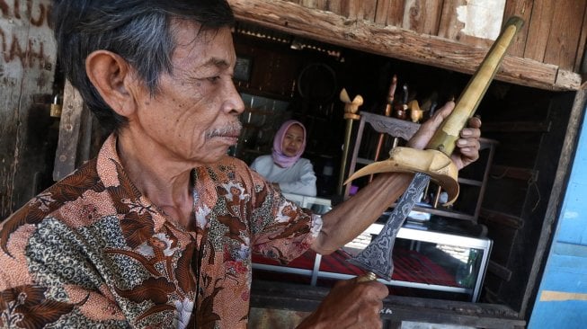 Pedagang pusaka memasukkan bilah keris ke dalam warangka usai dicuci di kawasan pasar Setonobetek, Kota Kediri, Jawa Timur, Selasa (2/9). [ANTARA FOTO/Prasetia Fauzani]