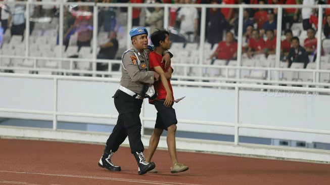 Polisi mengamankan suporter Indonesia yang berusaha menyerang suporter Malaysia saat pertandingan timnas Indonesia melawan timnas Malaysia pada Kualifikasi Piala Dunia 2022 Grup G Zona Asia di Stadion Gelora Bung Karno (GBK), Senayan, Jakarta, Kamis (5/9). [Suara.com/Arya Manggala]