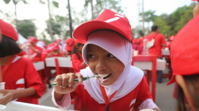 Un certain nombre d'élèves du primaire se brossent les dents ensemble dans le mouvement Smiling Indonesia lors du Mois national de la santé dentaire 2019 (BKGN) à Jakarta, samedi (7/9). [Suara.com/Arya Manggala]