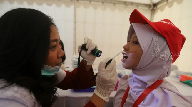 Dokter Gigi memeriksa gigi seorang siswa Sekolah Dasar dalam gerakan Indonesia Tersenyum di Bulan Kesehatan Gigi Nasional (BKGN) 2019 di Jakarta, Sabtu (7/9). [Suara.com/Arya Manggala] 