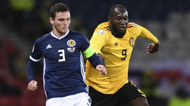 Striker Timnas Belgia, Romelu Lukaku beradu kuat dengan bek Skotlandia, Andrew Robertson pada kualifikasi Piala Eropa 2020 di Stadion Hampden Park, Glasgow, Selasa (10/92019). (ANDY BUCHANAN / AFP)