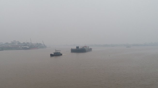 Dua kapal melintasi Sungai Kapuas yang diselimuti kabut asap pekat di Pontianak, Kalimantan Barat, Senin (9/9). [ANTARA FOTO/Rana Larasati]