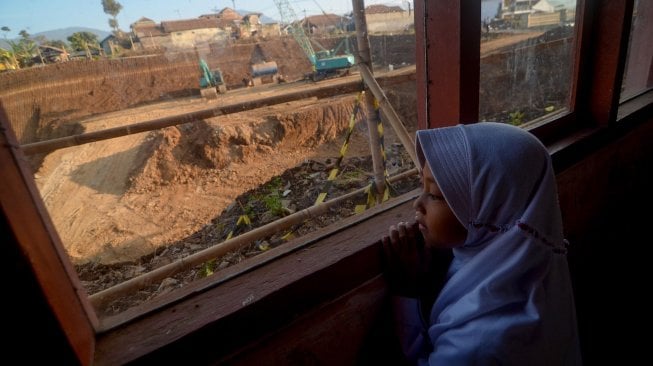 Seorang siswi mengamati alat berat dari dalam kelas SDN Cijolang yang terdampak proyek Tol Cisumdawu di Tanjungsari, Kabupaten Sumedang, Jawa Barat, Selasa (10/9). [ANTARA FOTO/Raisan Al Farisi]