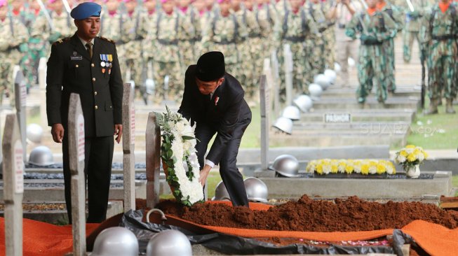 Presiden Joko Widodo selaku Inspektur Upacara meletakkan bunga di makam almarhum Presiden ke-3 RI BJ Habibie saat Upacara Pemakaman di Taman Makam Pahlawan Kalibata, Jakarta, Kamis (12/9). [Suara.com/Arya Manggala]
