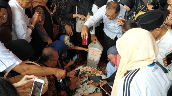 Usai pemakaman, warga yang menghadiri upacara tersebut mendatangi pusara Habibie untuk berfoto. (Suara.com/Fakhri Fuadi)