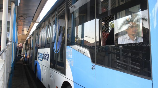 Bus Trans Jakarta menaikkan dan menurunkan penumpang di Halte Masjid Agung, Jakarta Selatan, Jumat (13/9). [Suara.com/ Angga Budhiyanto]