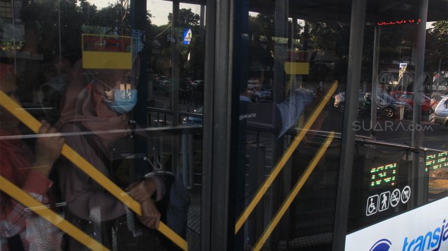 Bus Trans Jakarta menaikkan dan menurunkan penumpang di Halte Masjid Agung, Jakarta Selatan, Jumat (13/9). [Suara.com/ Angga Budhiyanto]
