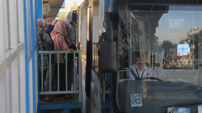 Bus Trans Jakarta menaikkan dan menurunkan penumpang di Halte Masjid Agung, Jakarta Selatan, Jumat (13/9). [Suara.com/ Angga Budhiyanto]
