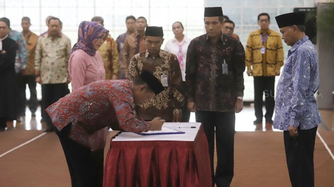 Fitroh Roncohyanto (kiri) melakukan penandatanganan saat pelantikan Sekjen dan Direktur Penuntut KPK yang baru di Gedung Merah Putih KPK, Jakarta, Senin (16/9). (Suara.com/Angga Budhiyanto)

