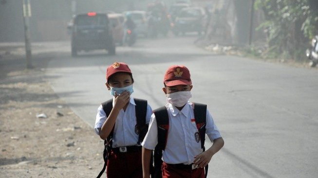 Siswa mengenakan masker saat pulang sekolah di sekitar lokasi kebakaran Tempat Pembuangan Akhir (TPA) Antang Makassar, Sulawesi Selatan, Senin (16/9/2019). (Antara)
