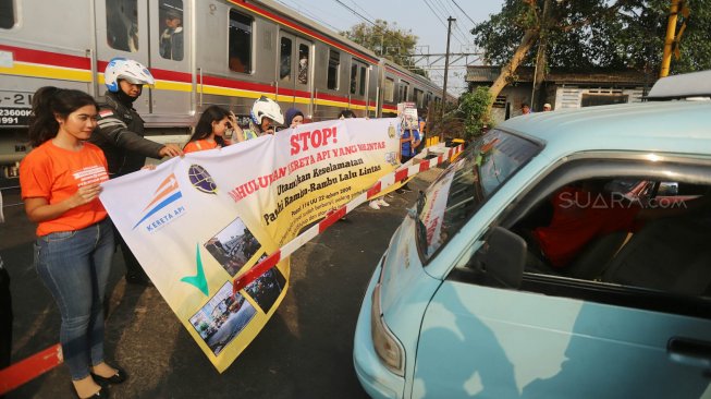 Petugas KAI Daop 1 Jakarta melakukan sosialisasi keselamatan di perlintasan sebidang Bukit Duri Manggarai, Jakarta, Selasa (17/9). [Suara.com/Arya Manggala]