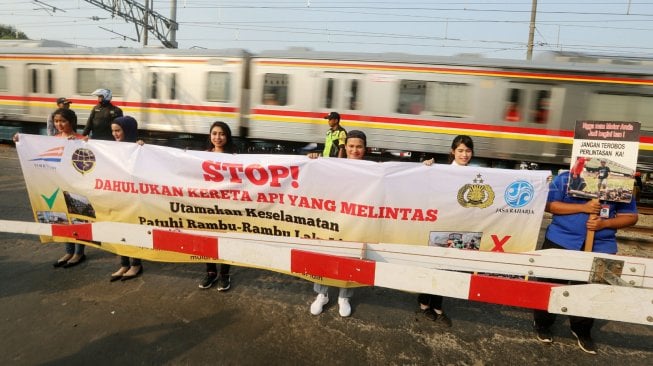 Petugas KAI Daop 1 Jakarta melakukan sosialisasi keselamatan di perlintasan sebidang Bukit Duri Manggarai, Jakarta, Selasa (17/9). [Suara.com/Arya Manggala]