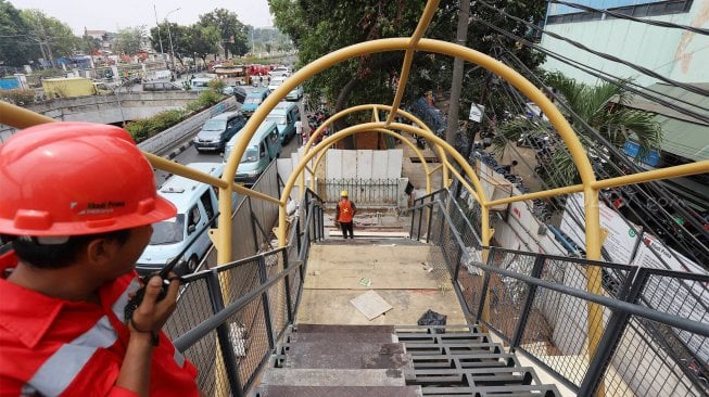 Pekerja menyelesaikan proyek jembatan penyeberangan orang (JPO) di kawasan Pasar Minggu, Jakarta Selatan, Selasa (17/9). [Suara.com/Angga Budhiyanto]
