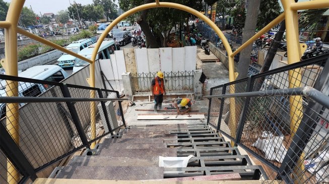 Pekerja menyelesaikan proyek jembatan penyeberangan orang (JPO) di kawasan Pasar Minggu, Jakarta Selatan, Selasa (17/9). [Suara.com/Angga Budhiyanto]
