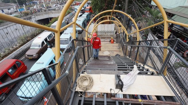 Pekerja menyelesaikan proyek jembatan penyeberangan orang (JPO) di kawasan Pasar Minggu, Jakarta Selatan, Selasa (17/9). [Suara.com/Angga Budhiyanto]
