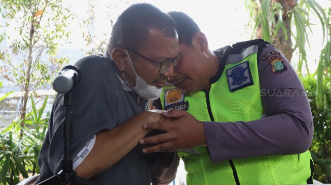 Bripka Eka Setiawan (tengah) berpelukan dengan pelaku di halaman Gedung Biru Polda Metro Jaya, Jakarta, Selasa (17/9).  [Suara.com/Angga Budhiyanto]