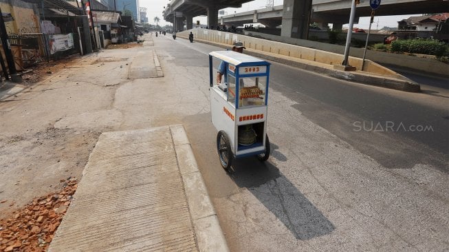 Sejumlah kendaraan melintas di samping trotoar yang berada di tengah jalan di Jalan Inspeksi Saluran Kalimalang, Jakarta, Rabu (18/9). [Suara.com/Angga Budhiyanto]