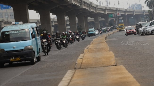 Sejumlah kendaraan melintas di samping trotoar yang berada di tengah jalan di Jalan Inspeksi Saluran Kalimalang, Jakarta, Rabu (18/9). [Suara.com/Angga Budhiyanto]