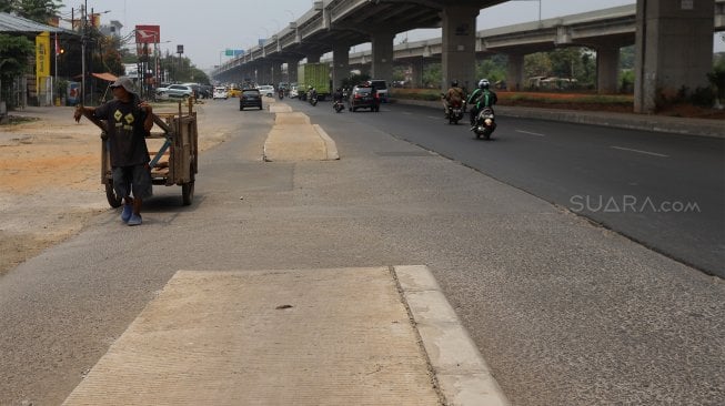 Sejumlah kendaraan melintas di samping trotoar yang berada di tengah jalan di Jalan Inspeksi Saluran Kalimalang, Jakarta, Rabu (18/9). [Suara.com/Angga Budhiyanto]