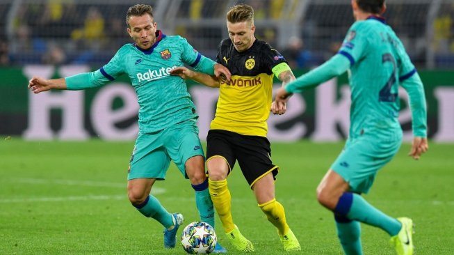 Penyerang Borussia Dortmund, Marco Reus (tengah) berduel dengan gelandang Barcelona, Arthur Melo pada babak penyisihan Grup F Liga Champions 2019/20 di Stadion Iduna Parka, Rabu (18/9/2019). (JOHN MACDOUGALL / AFP