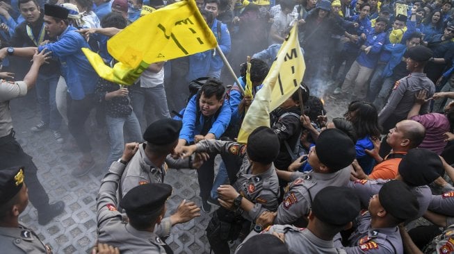 Mahasiswa yang tergabung dalam Pergerakan Mahasiswa Islam Indonesia (PMII) menyerang petugas kepolisian yang berusaha memadamkan api saat melakukan aksi unjuk rasa di depan gedung KPK, Jakarta, Jumat (20/9). [ANTARA FOTO/Muhammad Adimaja]