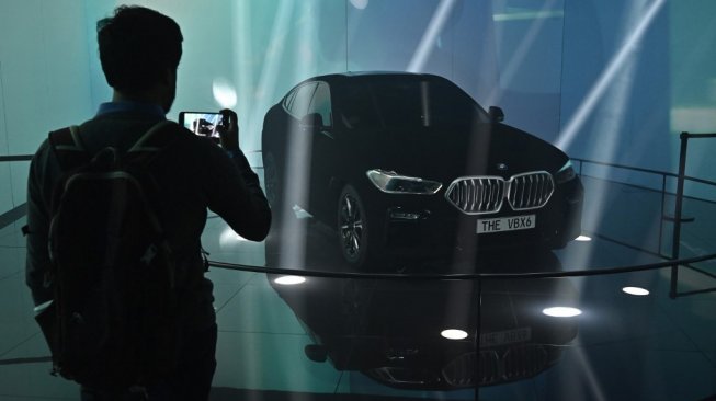 Seorang pengunjung pameran Frankfurt Motor Show sedang memotret BMW X6 Vantablack, yang diklaim sebagai mobil terhitam di dunia, pada 11 September 2019. [AFP/Tobias Schwarz]