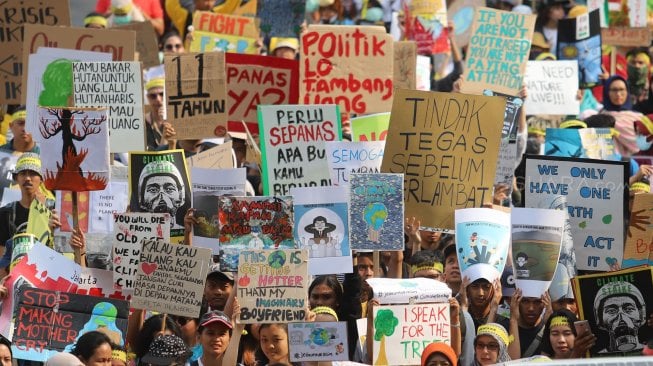 Aktivis dari berbagai organisasi lingkungan berjalan menuju Taman Aspirasi Monas saat aksi terkait krisis iklim di Jalan Medan Merdeka Barat, Jakarta Pusat, Jumat (20/9). [Suara.com/Arya Manggala]