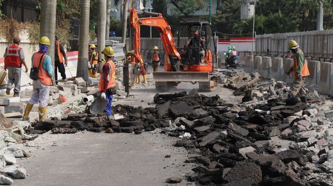 Pekerja menyelesaikan proyek revitalisasi trotoar di sekitaran Bundaran Hotel Indonesia, Jakarta, Minggu (22/9). [Suara.com/Angga Budhiyanto]