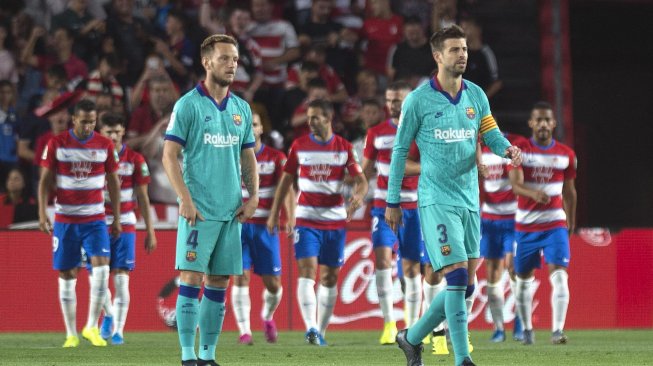 Gelandang Kroasia asal Ivan Rakitic dan bek Gerard Pique bereaksi terhadap gol gelandang Granada Ramon Azeez selama pertandingan sepak bola liga Spanyol antara Granada melawan Barcelona di Stadion Nuevo Los Carmenes, Granada, Spanyol, Minggu (22/9) dini hari WIB. 
[GUERRERO JORGE / AFP]
