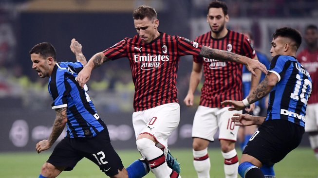 Pemain tengah AC Milan  Lucas Biglia menantang pemain tengah Inter Milan Stefano Sensi dan pemain depan Inter Milan Lautaro Martinez selama pertandingan sepak bola Serie A Italia antara AC Milan melawan Inter Milan di Stadion San Siro, Milan, Italia, Minggu (22/9) dini hari WIB. [Marco Bertorello / AFP]