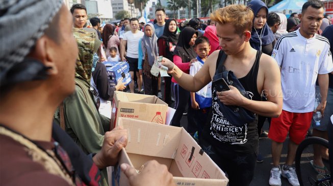 Warga memberikan sumbangan saat aksi penggalangan dana aksi sejuta masker di kawasan Bundaran Hotel Indonesia, Jakarta, Minggu (22/9). [Suara.com/Angga Budhiyanto] 
