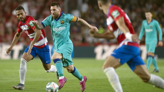 Pemain depan Barcelona Lionel Messi bersaing dengan gelandang Granada Antonio Puertas selama pertandingan sepak bola liga Spanyol antara Granada melawan Barcelona di Stadion Nuevo Los Carmenes, Granada, Spanyol, Minggu (22/9) dini hari WIB. [GUERRERO JORGE / AFP]