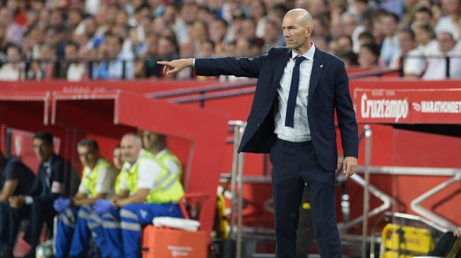 Pelatih Real Madrid, Zinedine Zidane memberi arahan kepada anak asuhnya saat menghadapi Sevilla pada Liga Spanyol 2019/20 di Stadion Ramon Sanchez Pizjuan, Senin (23/9/2019). (CRISTINA QUICLER / AFP)