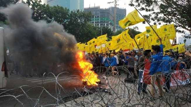 Massa yang berdemo di depan Gedung KPK melakukan aksi bakar ban bekas, Senin (23/9). (Suara.com/Fakhri).