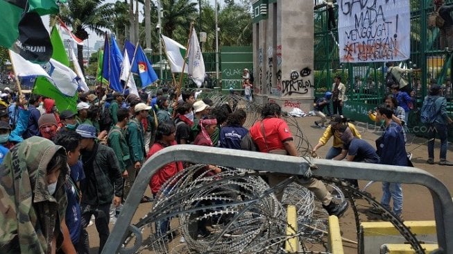 Massa dari elemen masyarakat dan mahasiswa menjebol kawat berduri di depan gedung DPR RI. (Suara.com/Fakhri)