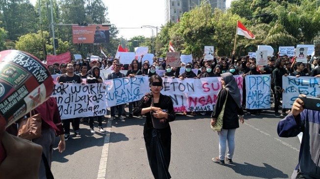 Aksi longmarch seorang demonstran wanita berkebaya hitam aksi tutup mata sambil menaburkan bunga. (Suara.com/Ari Purnomo).