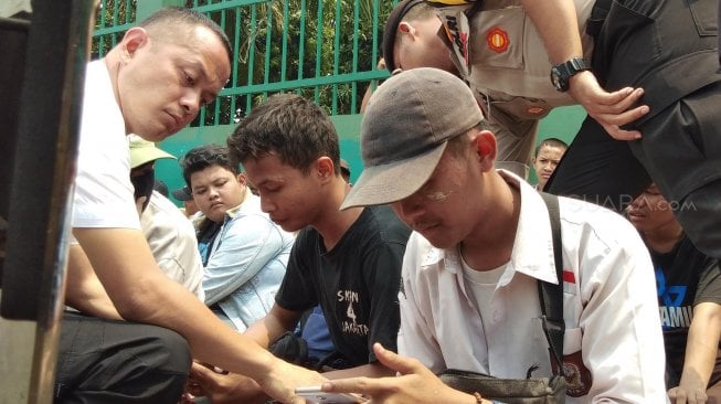 Sejumlah pelajar Sekolah Tingkat Menengah (STM) dijemur oleh petugas kepolisian di depan Gedung DPR-MPR, Jakarta, Rabu (25/9). [Suara.com/ Ria Rizki]
