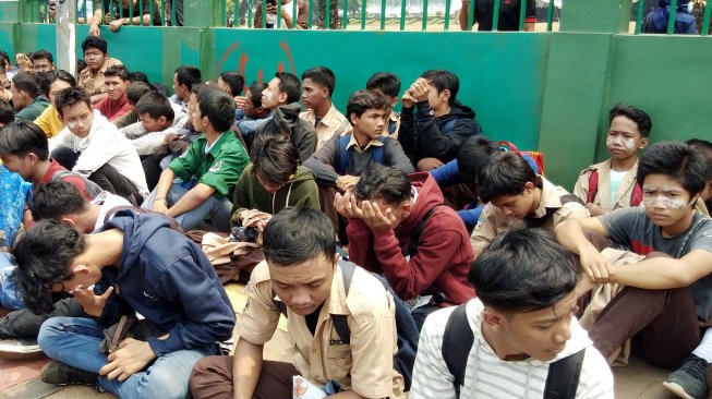 Sejumlah pelajar Sekolah Tingkat Menengah (STM) dijemur oleh petugas kepolisian di depan Gedung DPR-MPR, Jakarta, Rabu (25/9). [Suara.com/ Ria Rizki]
