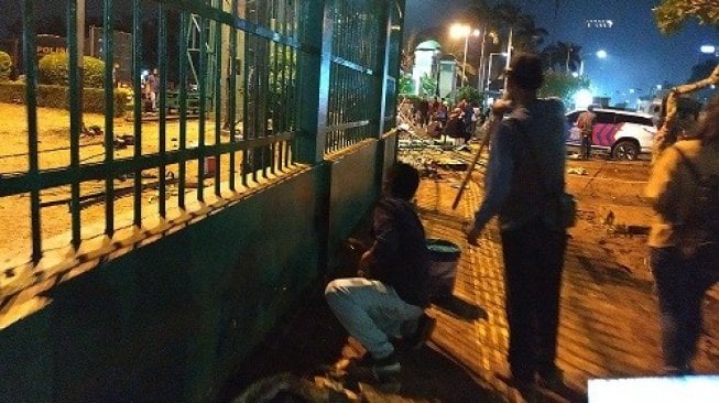 Petugas mengecat tembok pagar gedung DPR, Selasa (24/9/2019) malam. [Suara.com/Fakhri Fuadi]