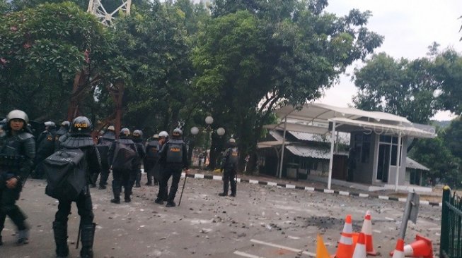 Balas gas air mata, pendemo dari kalangan pelajar lemparkan batu ke polisi di DPR. (Suara.com/Fakhri).