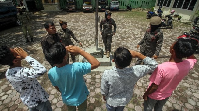 Sejumlah pelajar Sekolah Menengah Atas (SMA) yang membolos sekolah menjalani hukuman hormat bendera dibawah terik matahari saat diamankan petugas di kantor Satpol PP Lhokseumawe, Aceh, Kamis (26/9). [ANTARA FOTO/Rahmad]