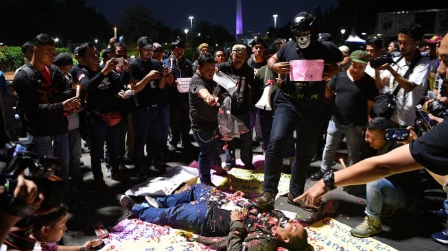 Sejumlah wartawan yang tergabung dalam Wartawan Hitam Jakarta menggelar aksi teatrikal di seberang Istana Merdeka, Jakarta, Kamis (26/9). [ANTARA FOTO/Sigid Kurniawan]